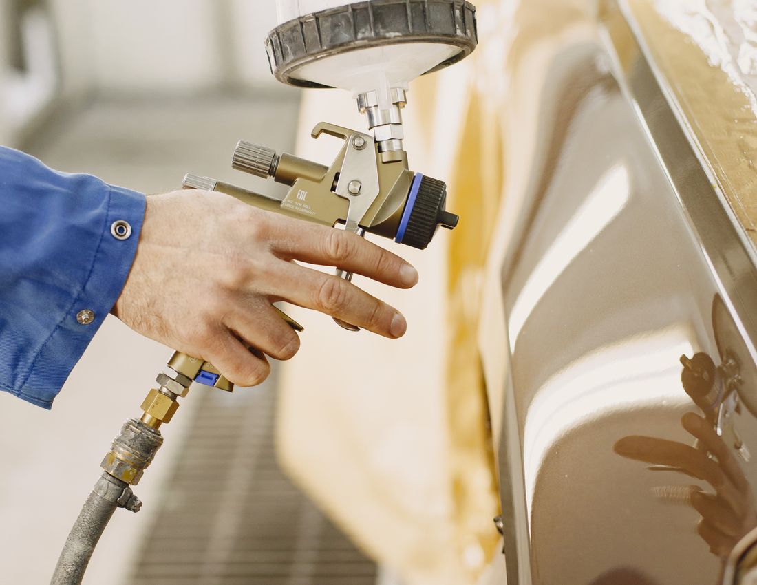 Auto body technician spray painting a car panel